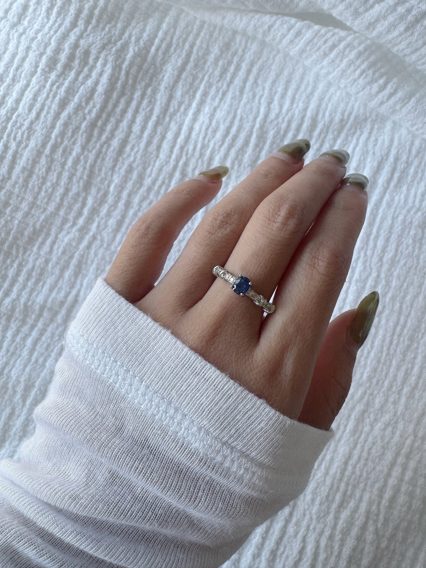 hand wearing blue sapphire silver ring