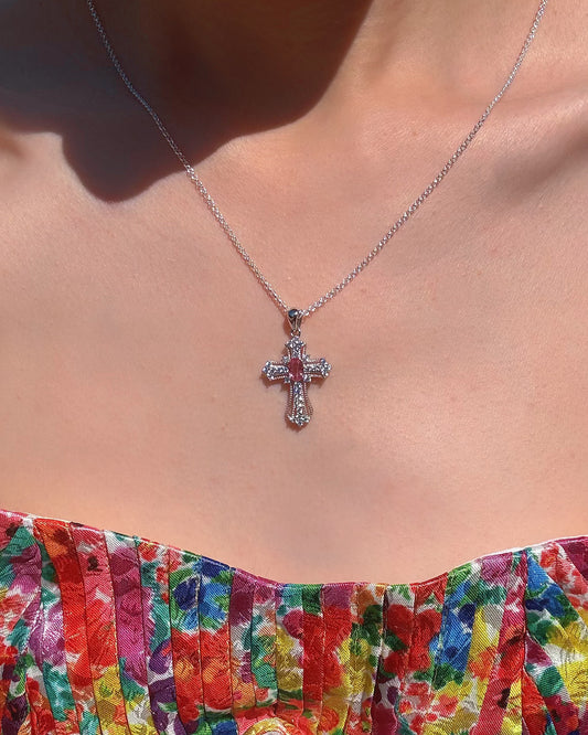 Cross necklace on a person wearing a colorful floral top.